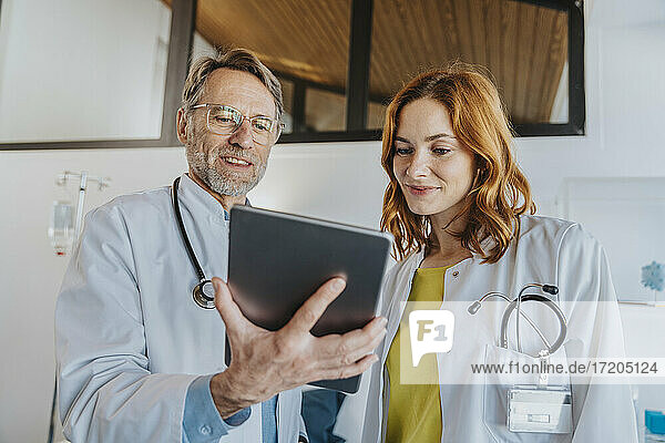 Mitarbeiter des Gesundheitswesens arbeiten im Stehen über ein digitales Tablet in einer Klinik