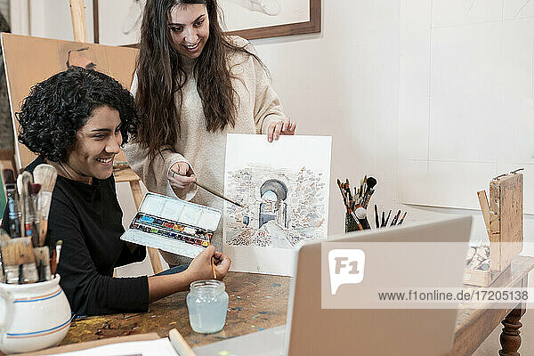 Künstlerinnen zeigen Gemälde während eines Videogesprächs im Atelier