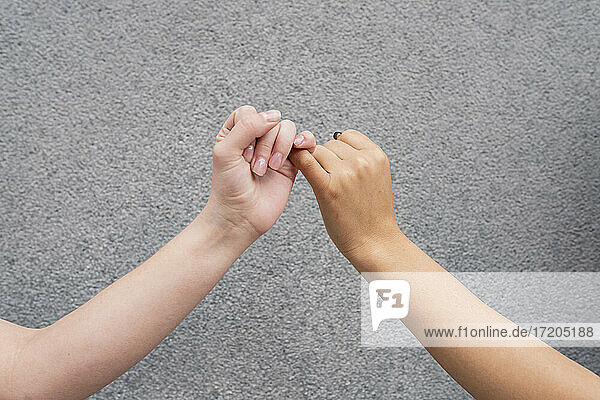 Hands of two women making pinky promise