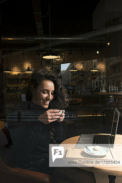 Smiling businesswoman drinking coffee sitting at cafe
