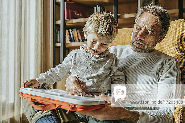 Boy learning drawing from father while sitting on lap