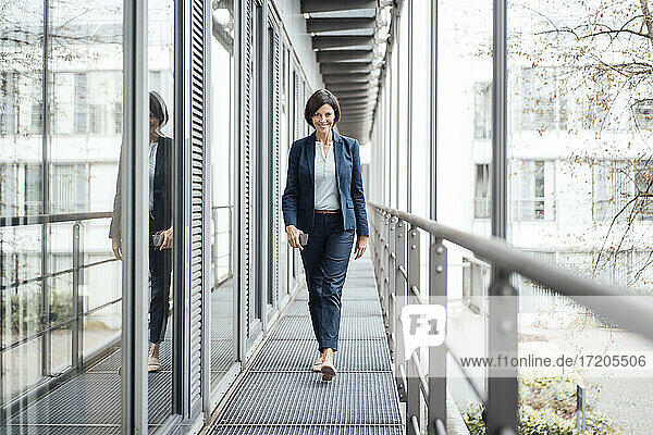 Smiling female entrepreneur walking in office balcony