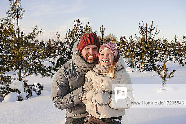 Smiling father and daughter in warm clothing during sunset