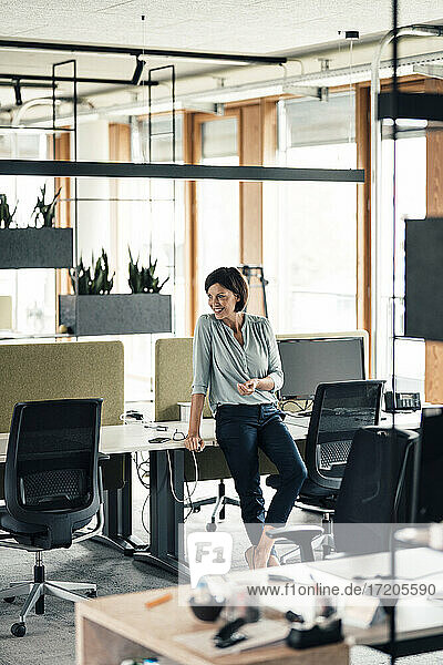 Unternehmerin lehnt sich im Büro an den Schreibtisch