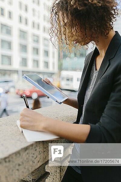 Junge Geschäftsfrau schreibt mit digitalem Tablet in ihr Tagebuch