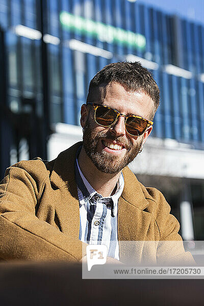 Mittlerer Erwachsener Geschäftsmann lächelnd im Freien sitzend an einem sonnigen Tag