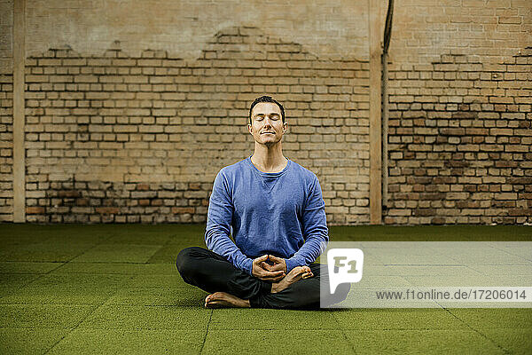 Mann meditiert an der Wand im Fitnessstudio