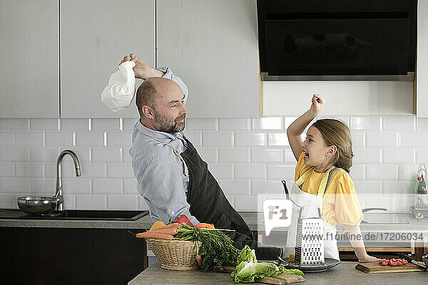 Verspielter Vater und Tochter geben sich High-Five  während sie in der Küche zu Hause stehen