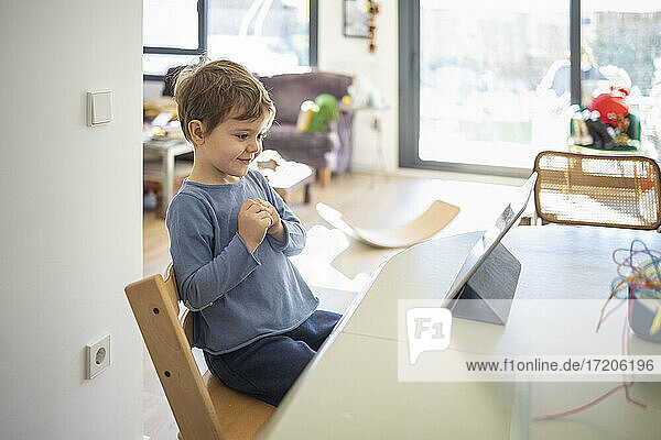 Lächelnder Junge besucht Online-Kurs auf digitalem Tablet zu Hause