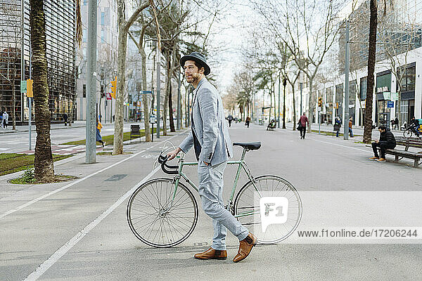 Männlicher Unternehmer zu Fuß mit Fahrrad auf der Straße in der Stadt