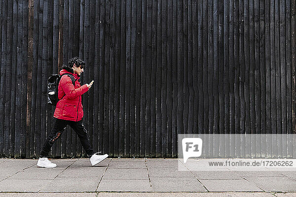 Mann benutzt Mobiltelefon beim Gehen auf dem Fußweg