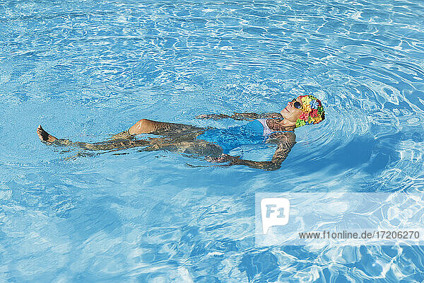 Frau entspannt sich im klaren blauen Schwimmbad
