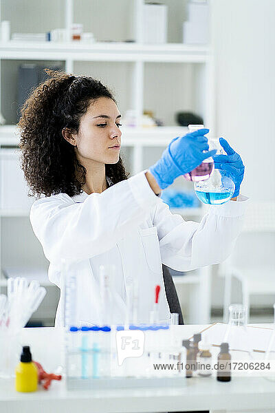 Junge Forscherin  die eine chemische Lösung in einem Becherglas im Krankenhaus testet