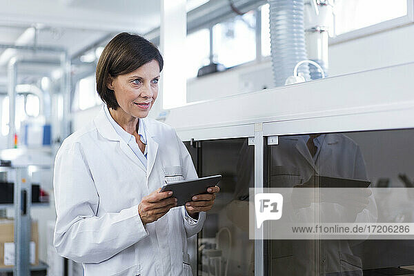 Weiblicher Techniker mit digitalem Tablet  der in der Fabrik wegschaut