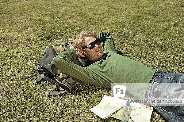 Male tourist lying down on grass in public park during weekend