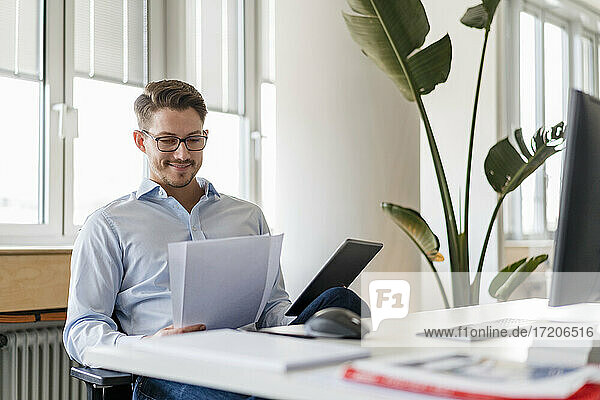 Männlicher Unternehmer mit Dokument und digitalem Tablet im Büro