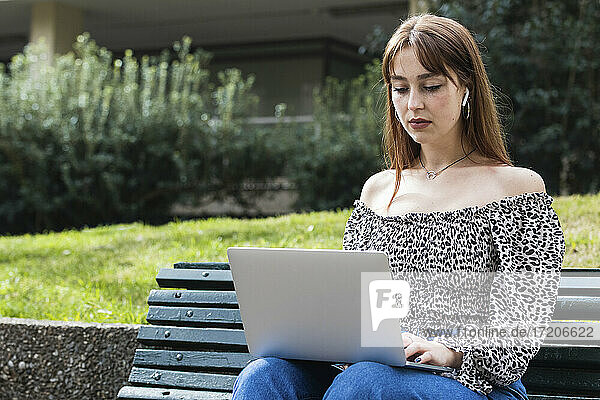 Unternehmerin  die einen Laptop benutzt  während sie auf einer Bank sitzt