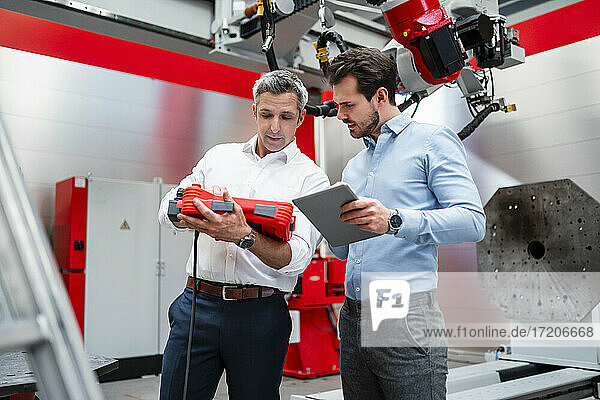 Male engineers working with robotic equipment in factory