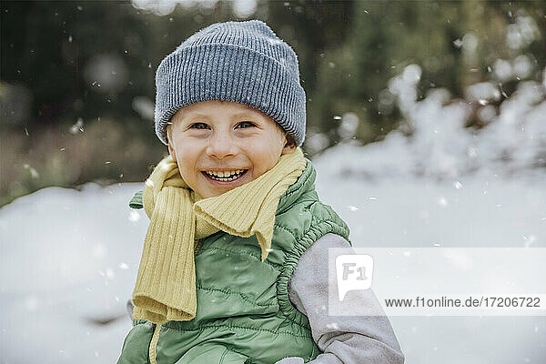 Smiling cute boy on snow covered land while snowing during winter