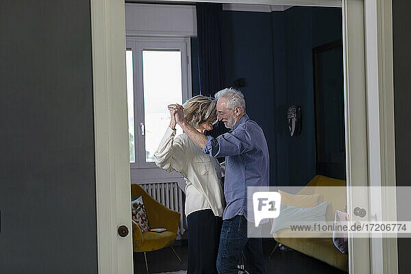 Zärtliches älteres Paar hält sich beim Tanzen zu Hause an den Händen
