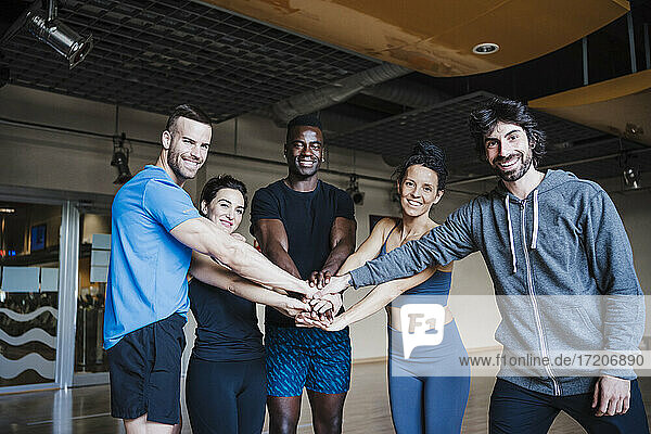 Smiling multi-ethnic group of sports people huddling in gym
