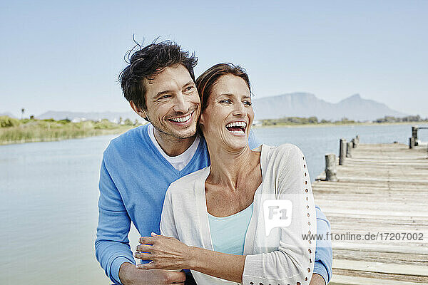 Cheerful woman sitting with smiling man on pier