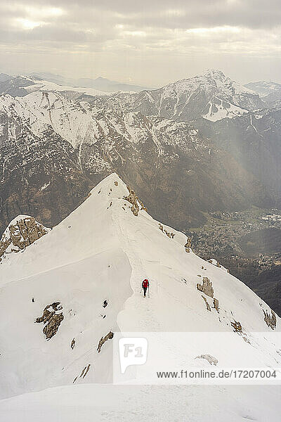 Trekker  der auf einem schneebedeckten Berg vor einer schönen Bergkette wandert