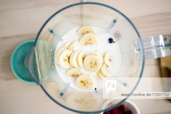 Frische Bananen und Milch im Mixer auf dem Tisch