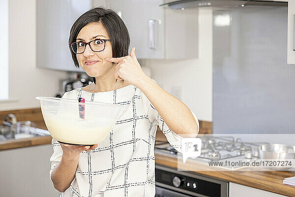 Woman preparing cheesecake filling and making hand gesture to say it is delicious