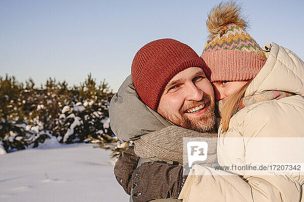 Smiling father embracing daughter in warm clothing during winter
