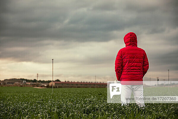 Caucasian man with winter coat standing in field against cloudy sky