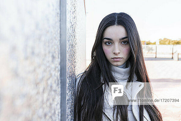 Confident teenage girl by silver wall on sunny day