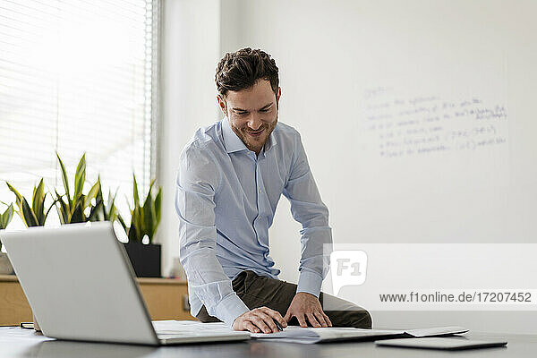 Smiling male entrepreneur examining blueprint at office