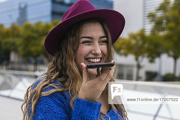 Glückliche Frau lacht beim Senden einer Sprachnachricht über ein Mobiltelefon
