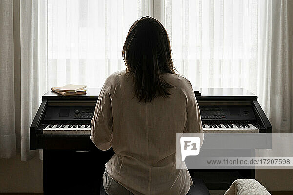Young woman playing piano at home