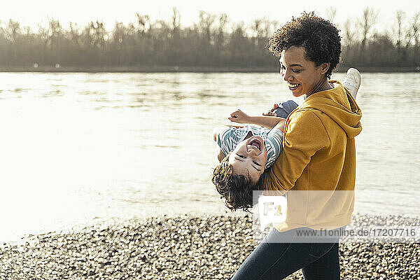 Lächelnde Mutter mit fröhlichem Jungen auf dem Arm am See