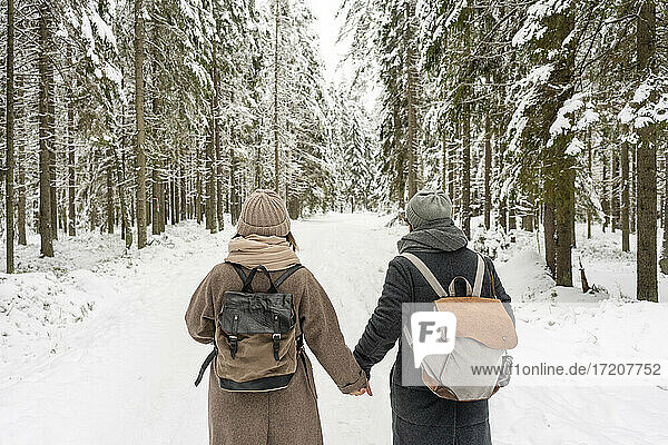 Paar mit Rucksack  das sich im Wald an den Händen hält