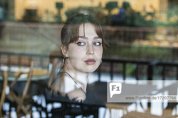 Schöne Frau mit Pony  die durch das Fenster eines Cafés schaut