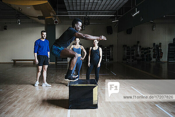 Young male sportsperson jumping on box in health studio