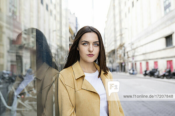 Woman with blue eyes by glass wall in city