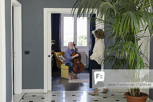 Ältere Frau  die einen Mann beim Cellospielen beobachtet  während sie zu Hause sitzt