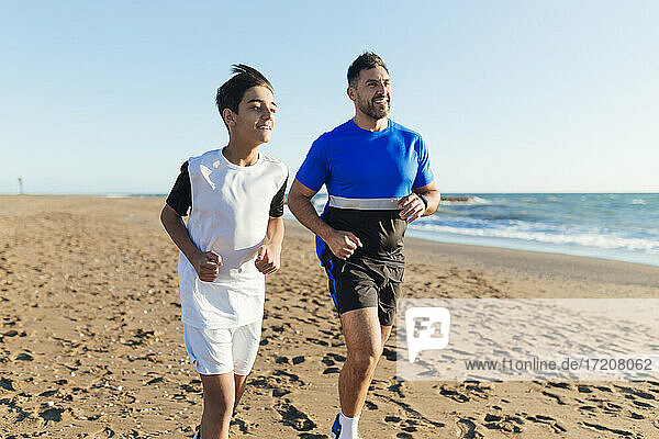 Smiling father and son running at beach