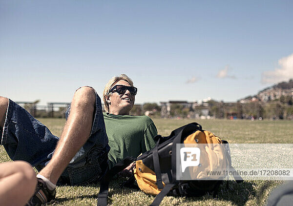 Junger Mann entspannt sich im Park an einem sonnigen Tag am Wochenende