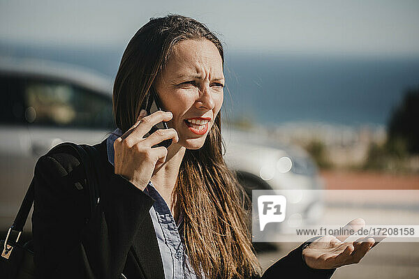 Angry businesswoman talking on mobile phone during sunny day