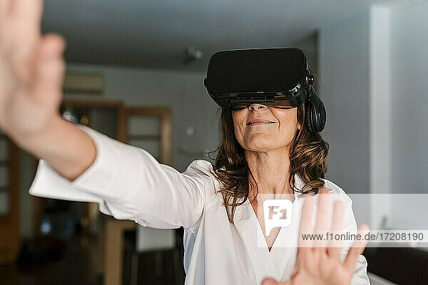 Frau lächelt bei der Verwendung eines Virtual-Reality-Headsets zu Hause