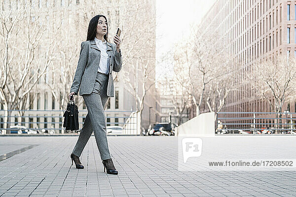 Reife Geschäftsfrau im Gespräch auf dem Smartphone beim Spaziergang in der Stadt