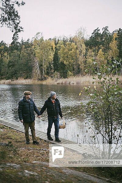Homosexuelles Paar hält Hände beim Spaziergang am Flussufer