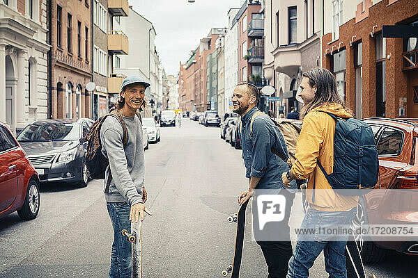 Glückliche Freunde reden,  während sie mit Skateboards auf der Straße in der Stadt stehen