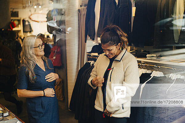 Female customer with warm jacket standing by businesswoman at retail store