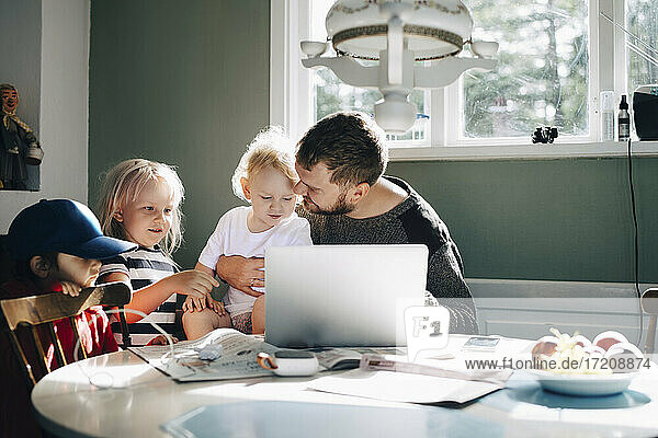 Father with children using laptop over table at home